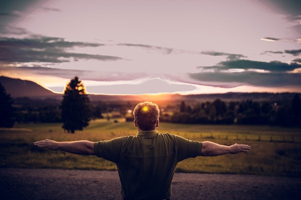 A man stretching in a field under the sun.